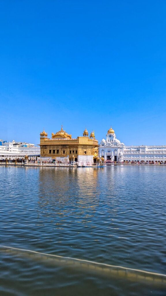 Stunning view of the Golden Temple and its reflection in Amritsar, India under a clear blue sky.