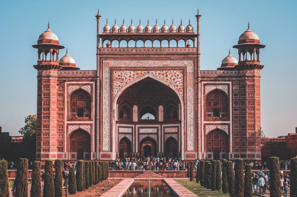 Magnificent scenery of facade of Taj Mahal with crowd of tourists near entrance on sunny day with blue sky in Agra